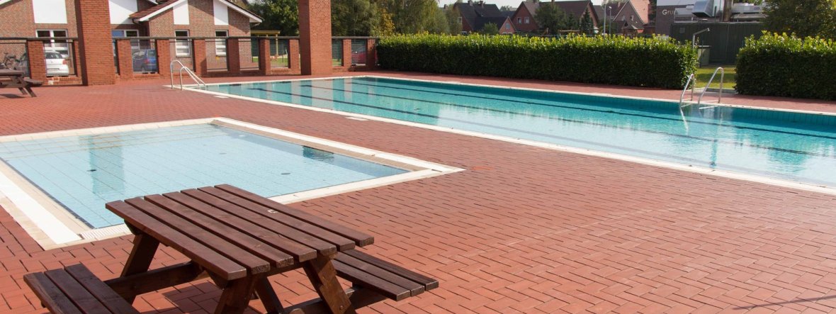 Ein kleinen Schwimmbecken und ein großes Schwimmbecken und ein Gebäude im Hintergrund 