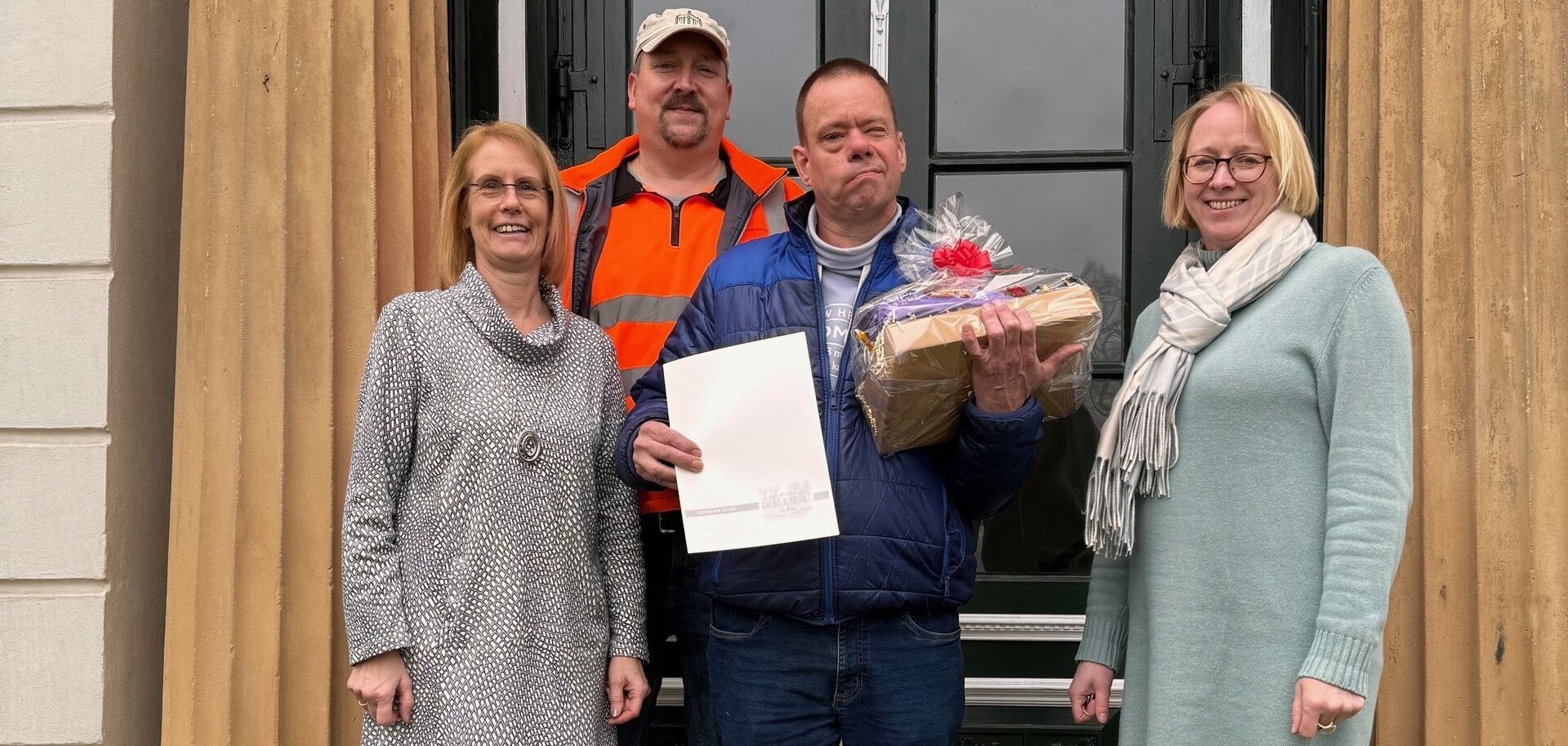 Ein Bild mit vier Personen vor dem Rathaus