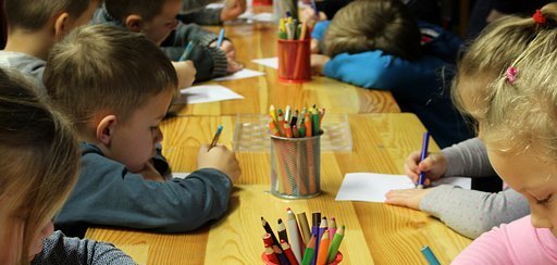 Kinder sitzen an einem Tisch und malen 