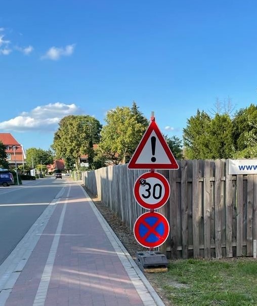 Eine Frau überreicht einer anderen Frau eine Blume und im Hintergrund sitzen ein paar kleine Kinder 