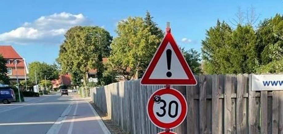 Eine Frau überreicht einer anderen Frau eine Blume und im Hintergrund sitzen ein paar kleine Kinder 