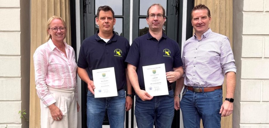 Ein Bild mit vier Personen vor einem Eingang