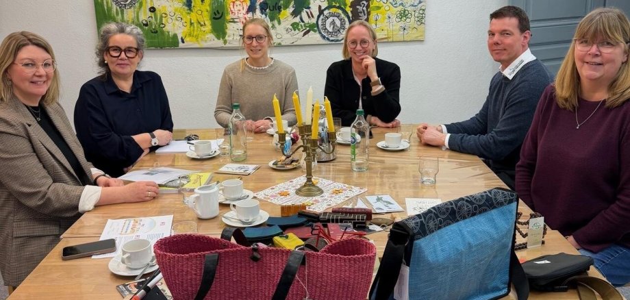 Ein Bild mit Personen am Tisch