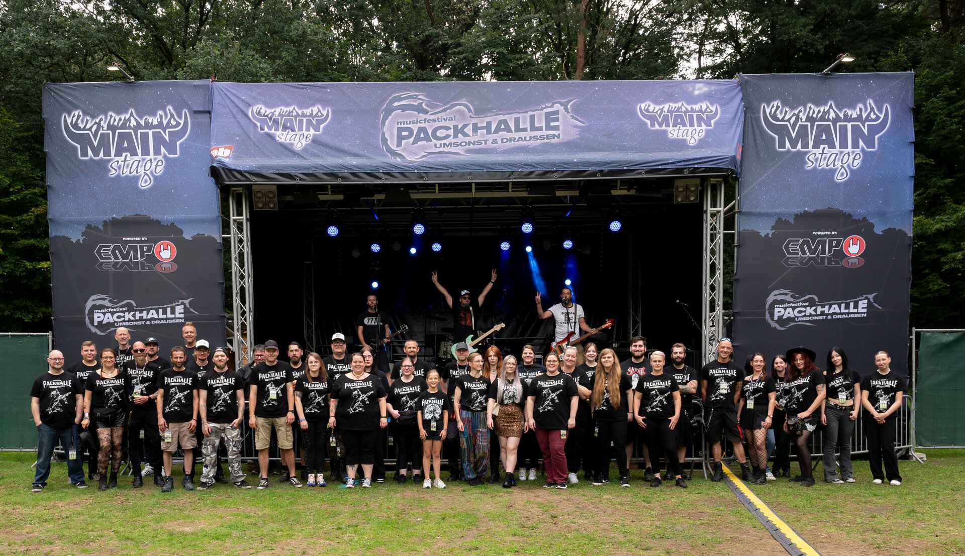 Ein Bild mit vielen Personen vor einer Bühne