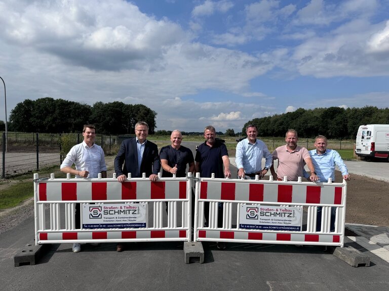 Ein Bild mit 7 Personen auf einer Straße mit einer Absperrung