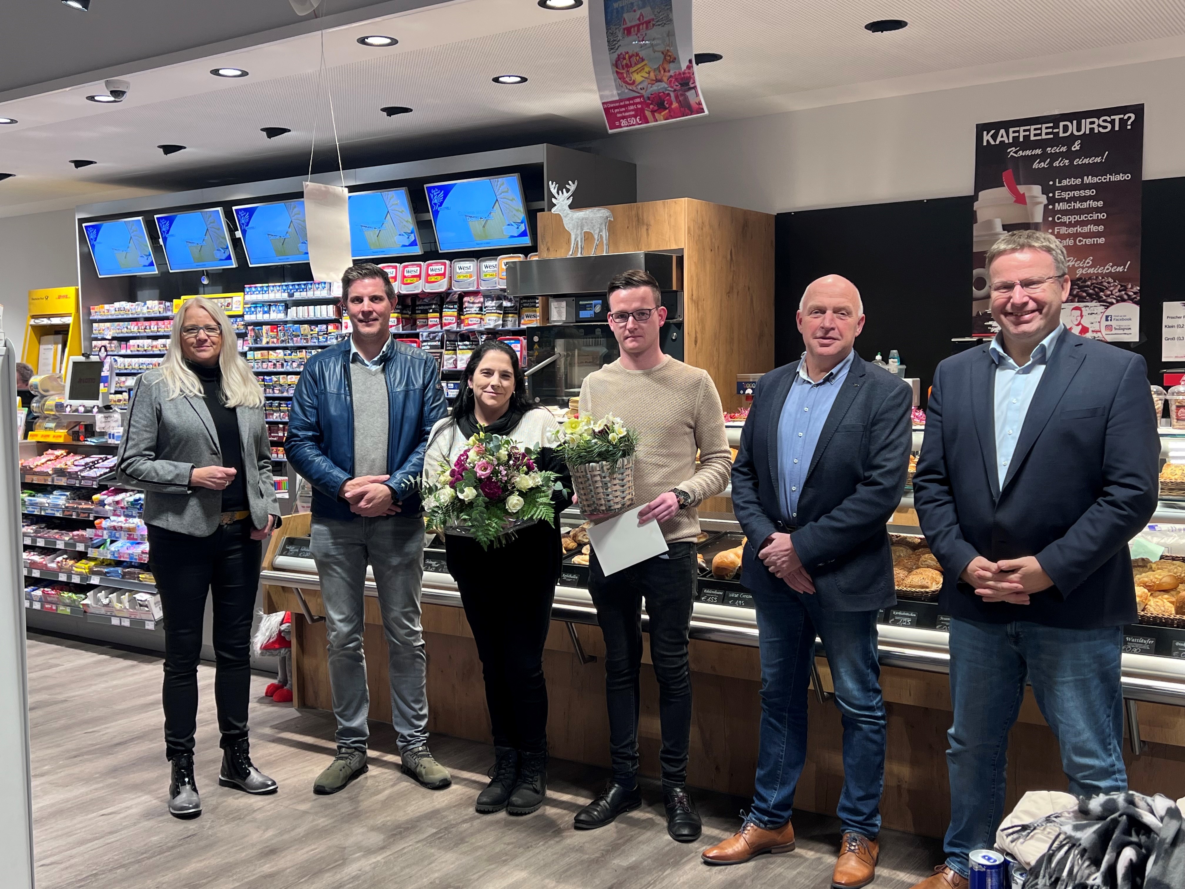 Ein paar Leute stehen in einem Kiosk und halten Blumen in der Hand 