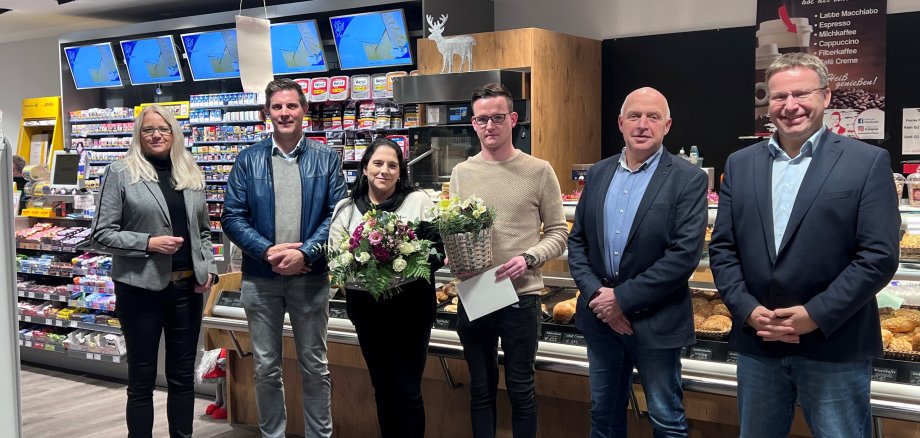 Ein paar Leute stehen in einem Kiosk und halten Blumen in der Hand 