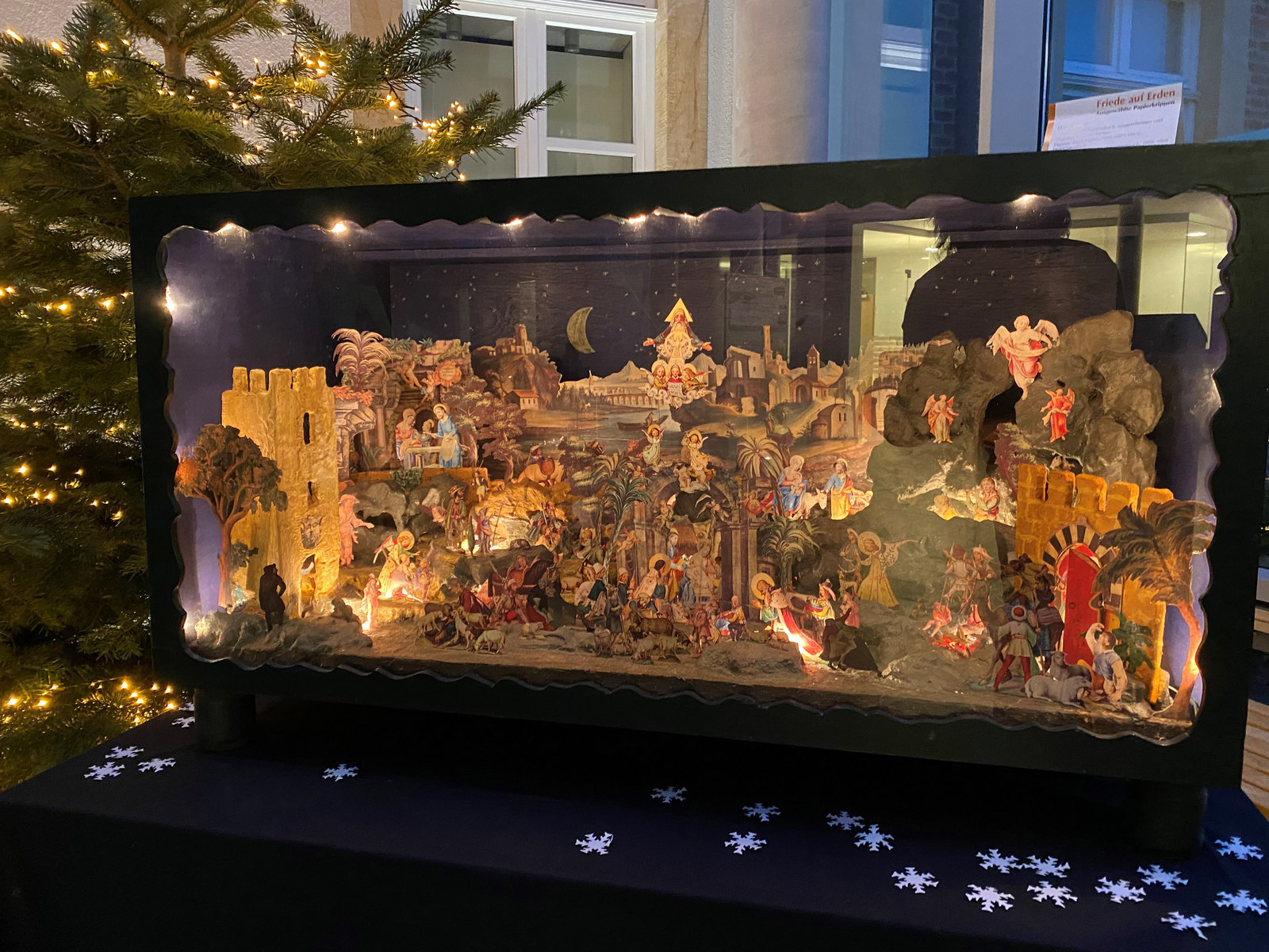 Papierkrippe vor einem Weihnachtsbaum 