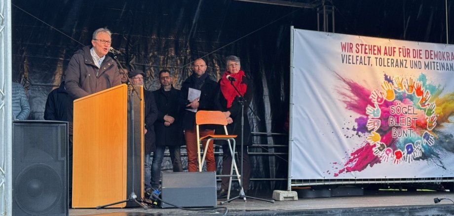 Ein Bild mit einem Redner und mehreren Personen 