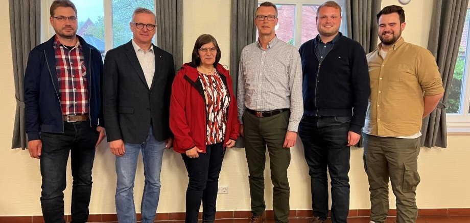 Ein Bild mit Personen vor einer Wand