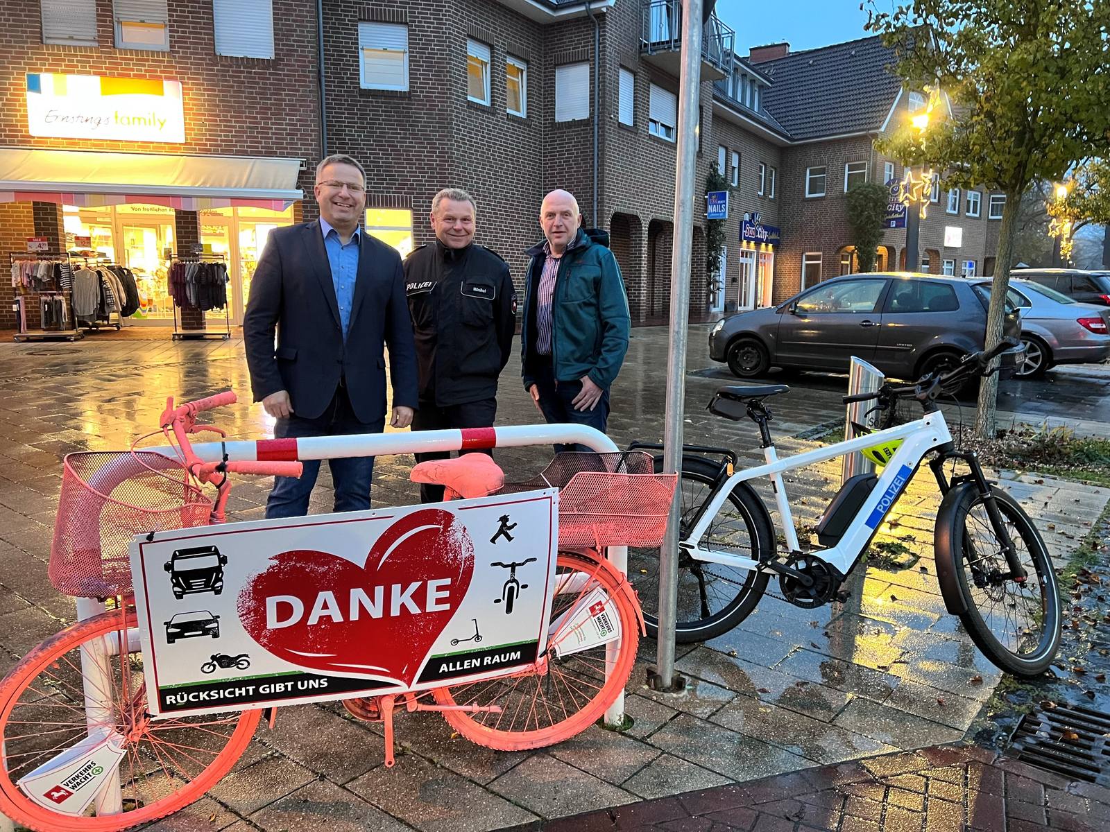 Zwei Männer stehen neben einem Polizisten und vor Ihnen steht ein Fahrrad mit einem Plakat auf dem Danke steht 