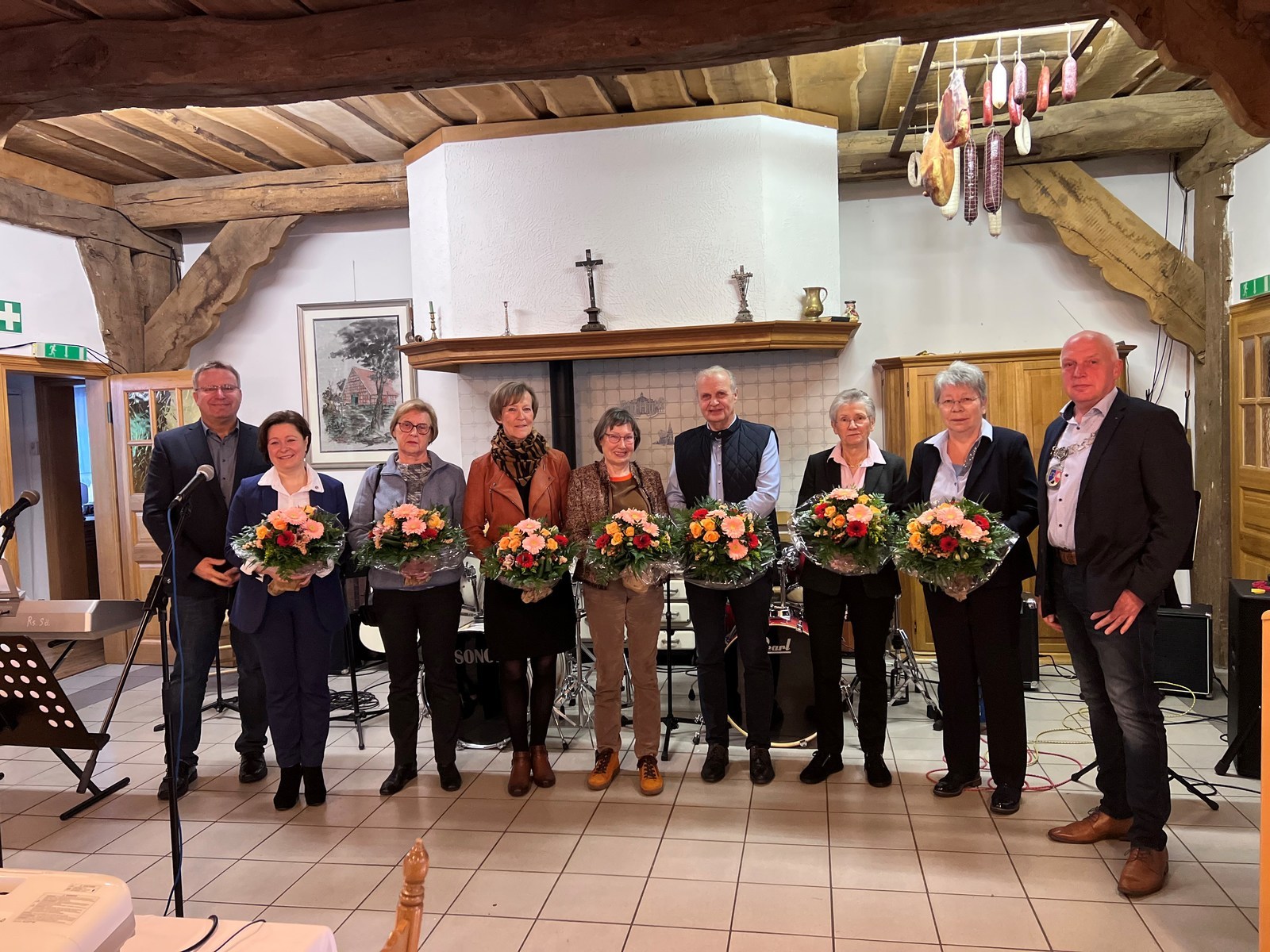 Einige Leute stehen in einem Raum nebeneinander und halten Blumensträuße in den Händen