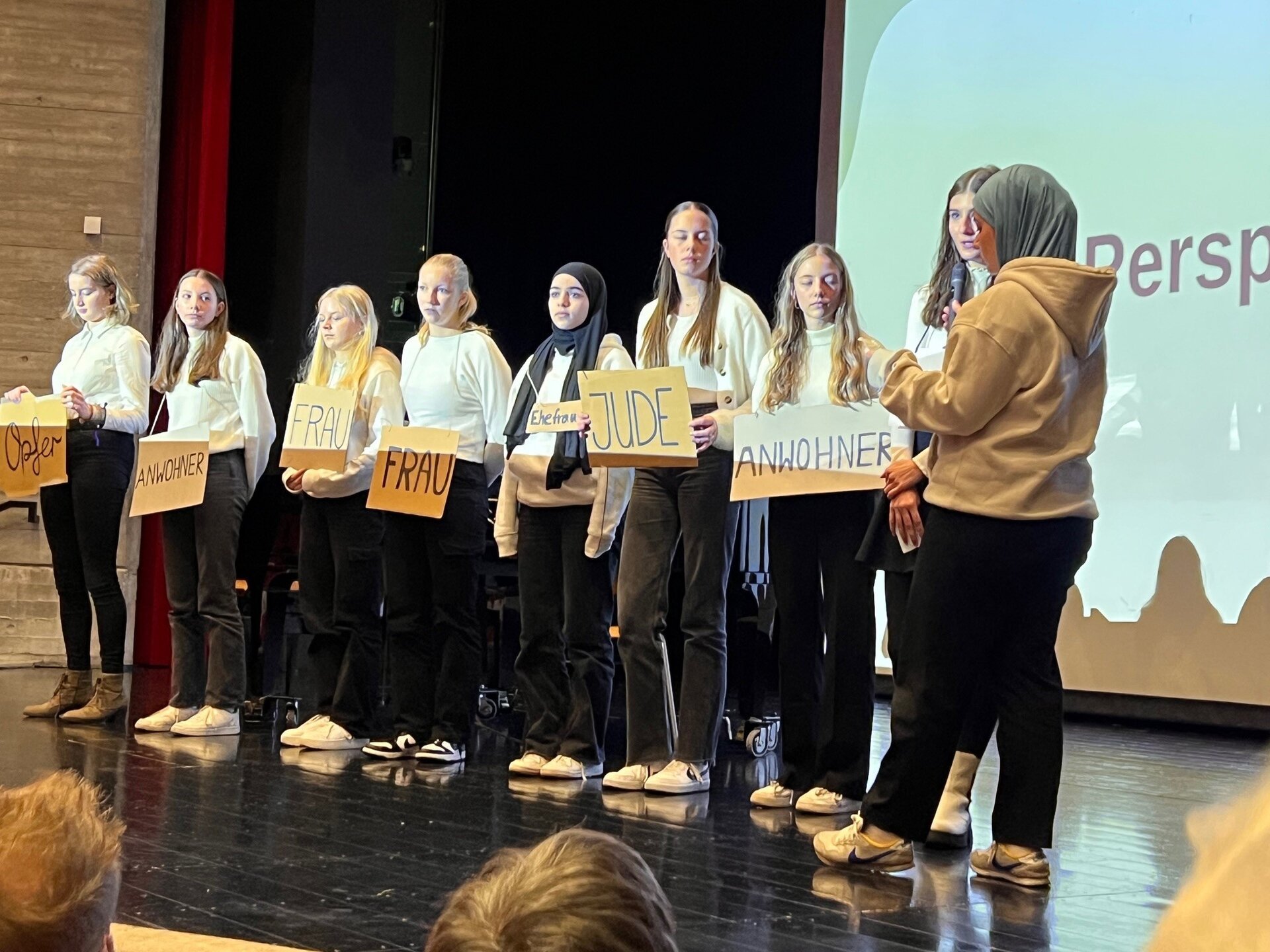 Ein Bild mit mehreren Personen in einer Aula