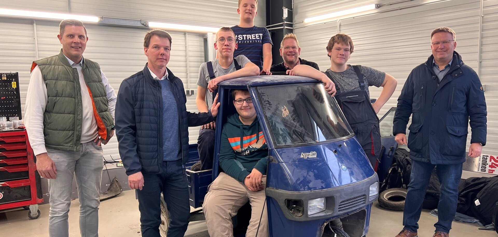 Ein Bild mit mehreren Personen vor einem Auto