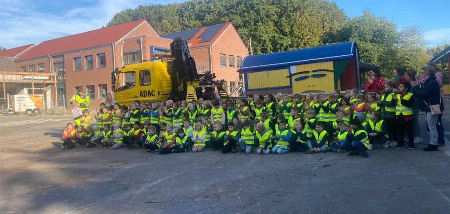 Viele Kinder tragen eine gelbe Warnweste und stehen vor einem ADAC LKW 