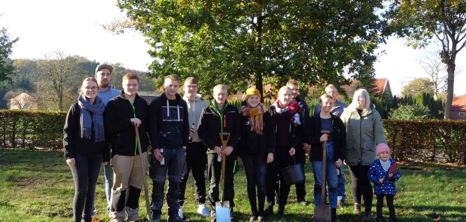 Junge Leute mit Schippe und Eimer in der Hand auf einer Wiese 