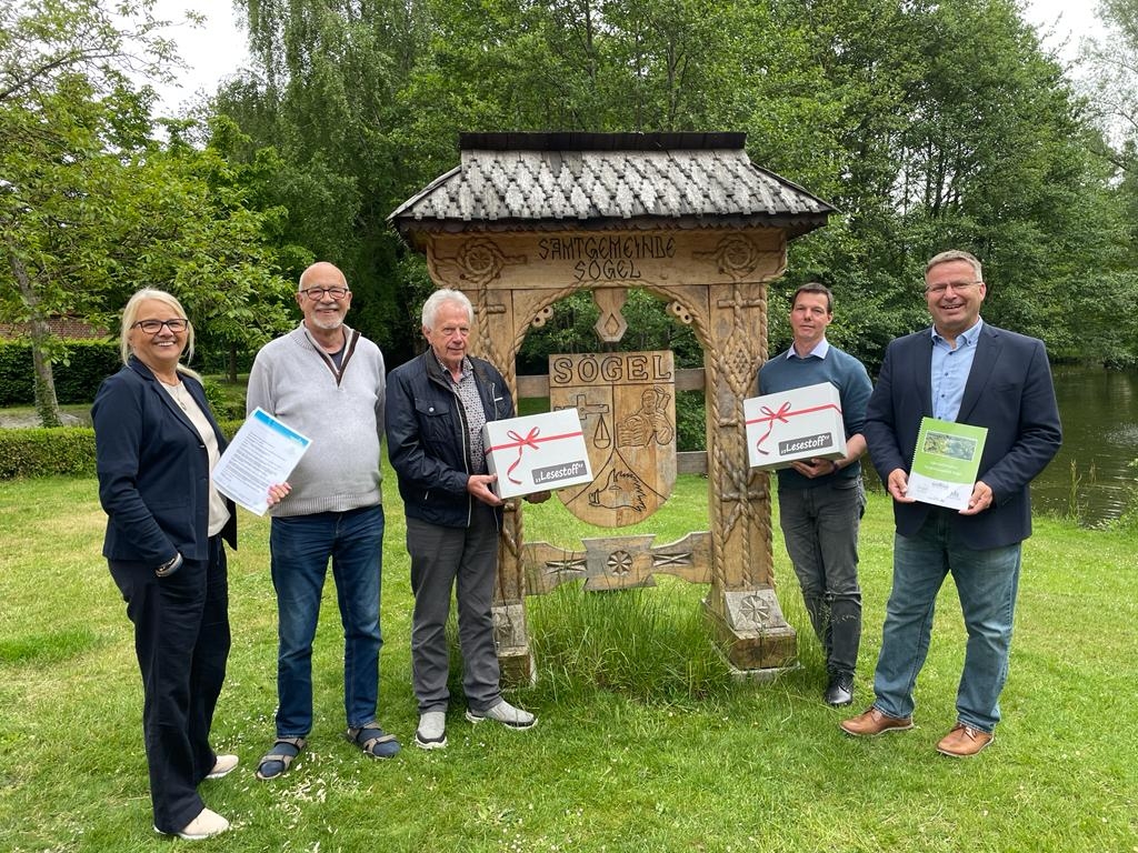 Einige Leute stehen auf einer Wiese und halten eine Kiste in der Hand 