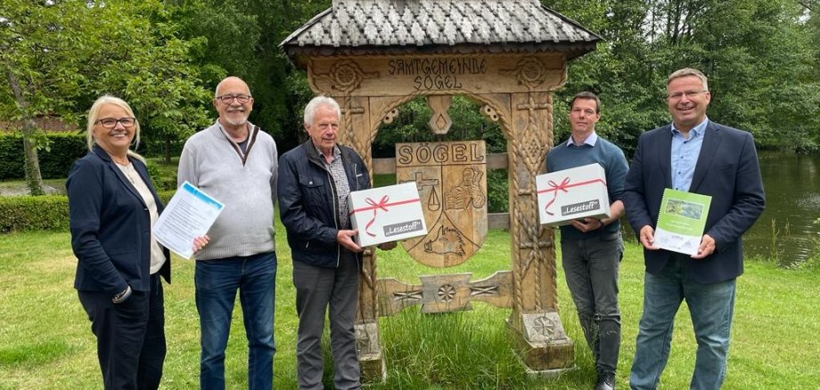 Einige Leute stehen auf einer Wiese und halten eine Kiste in der Hand 