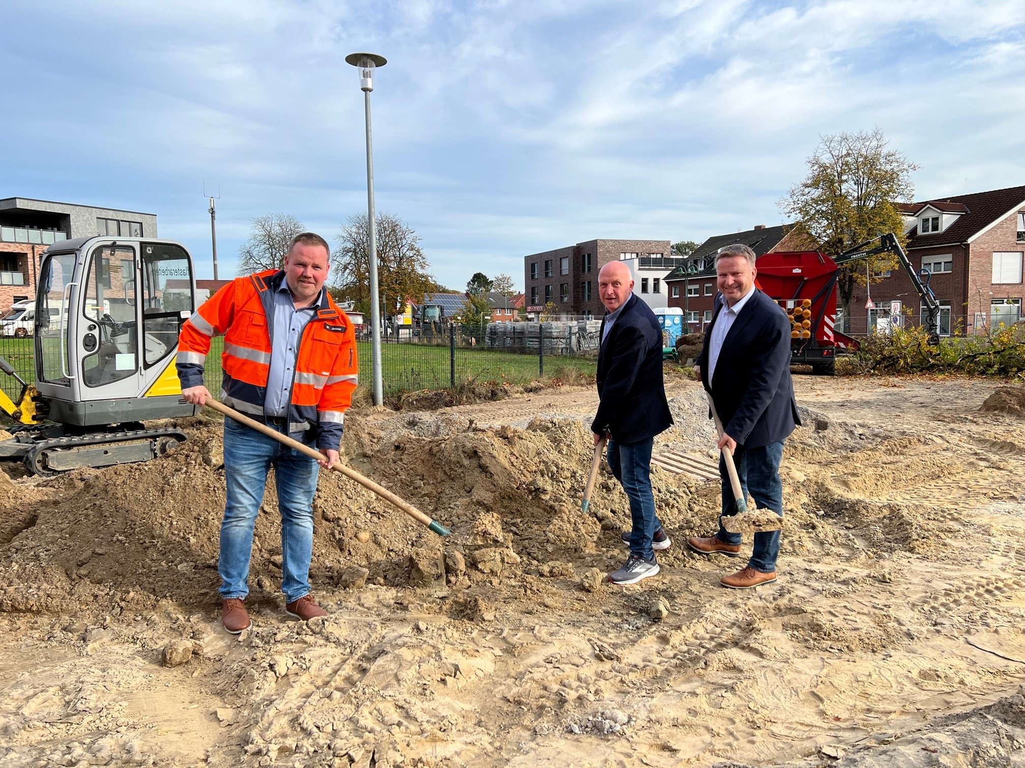 Drei Männer mit einer Schaufel in der Hand die vor einem Sandhaufen stehen 