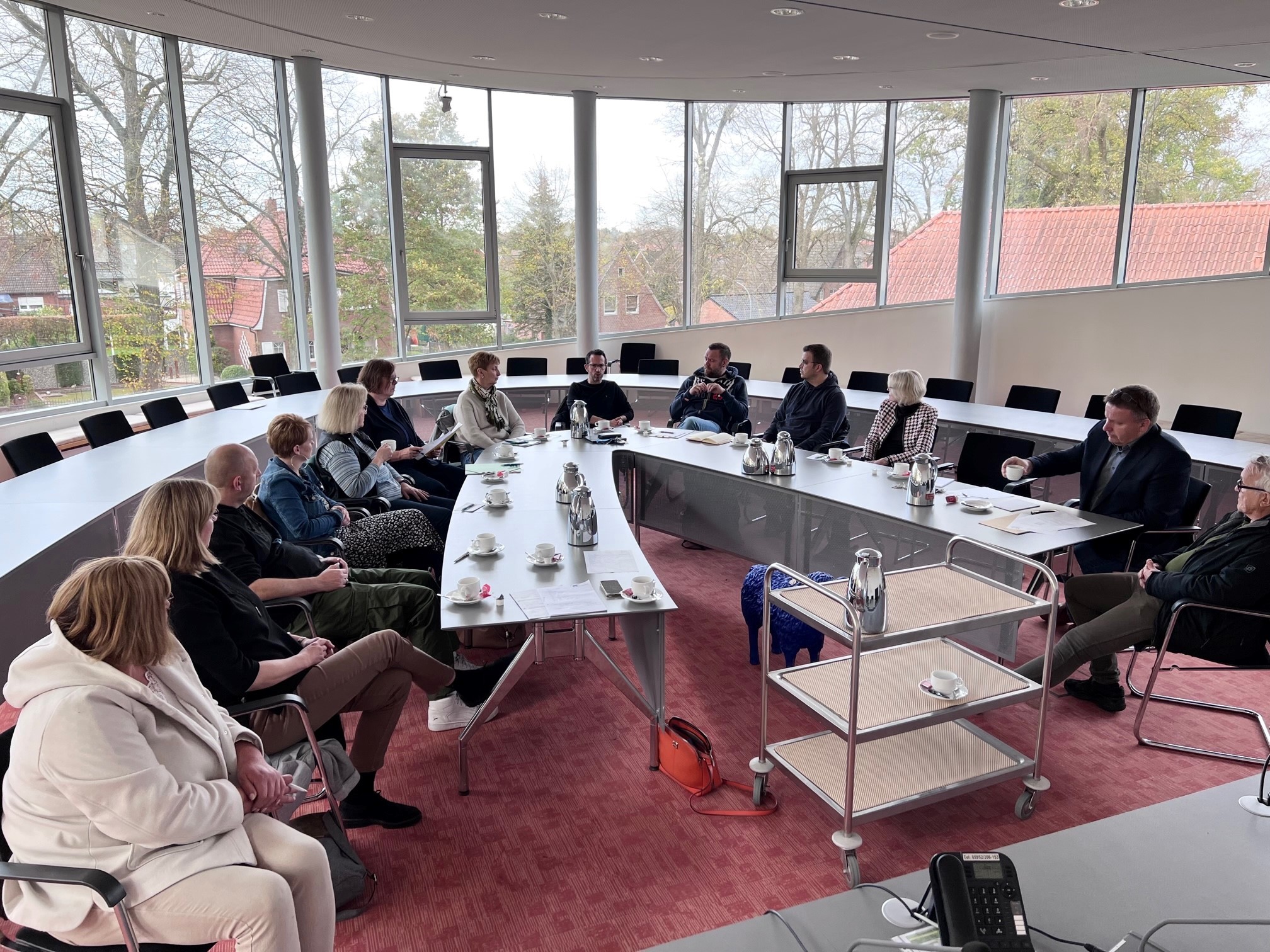 Einige Erwachsene Leute sitzen an einem halbrunden Tisch 