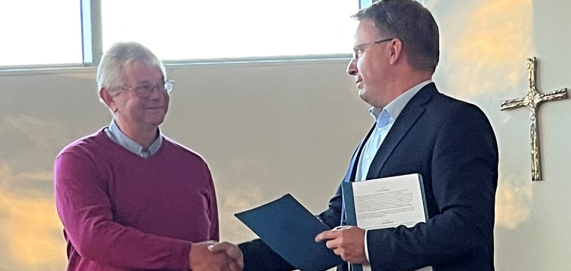 Ein Bild mit zwei Personen die sich die Hände reichen