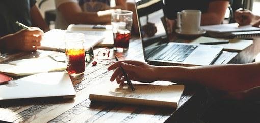 Ein Tisch auf dem Blöcke, Unterlagen und Laptops liegen