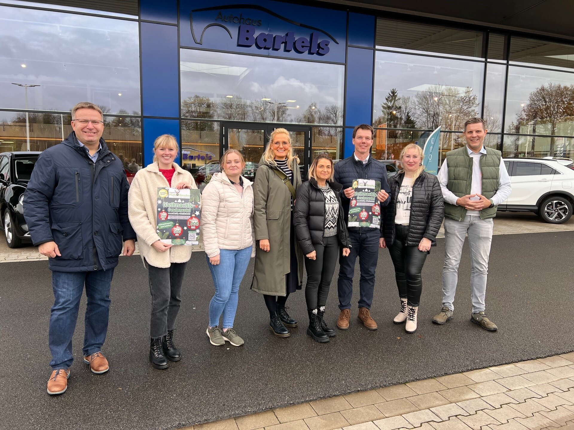 Ein Bild mit mehreren Personen vor einem Autohaus