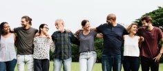 Unterschiedliche Leute stehen in einer Reihe und halten ihre arme um ihre Nachbarn
