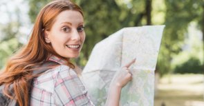 Eine Frau hält eine Landkarte in der Hand und zeigt mit einem Finger drauf 